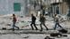Rebels run across bombed street Rebels run across bombed street