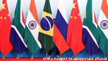 Staff worker stands behinds national flags of Brazil, Russia, China, South Africa and India to tidy the flags ahead of a group photo during the BRICS Summit at the Xiamen International Conference and Exhibition Center in Xiamen, southeastern China's Fujian Province, Monday, Sept. 4, 2017. (Wu Hong/Pool Photo via AP)