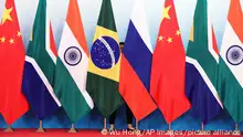 Staff worker stands behinds national flags of Brazil, Russia, China, South Africa and India to tidy the flags ahead of a group photo during the BRICS Summit at the Xiamen International Conference and Exhibition Center in Xiamen, southeastern China's Fujian Province, Monday, Sept. 4, 2017. (Wu Hong/Pool Photo via AP)