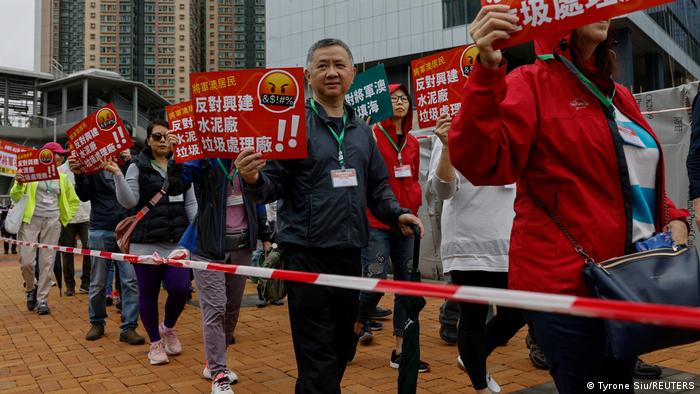 3月26日，香港人上街抗議將軍澳填海工程，卻遭警方要求配戴掛頸卡牌。