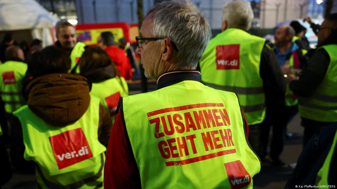 The bib of a worker participating in the protest at the entrance of Frankfurt airport reads 