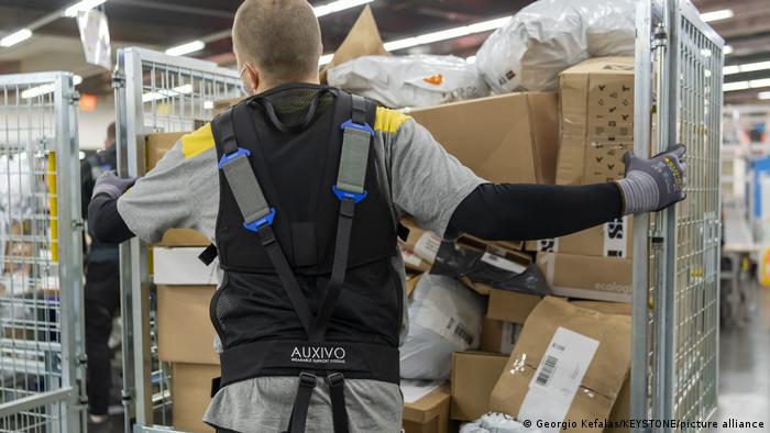 Angestellter im Paketzentrum mit Exoskelett 