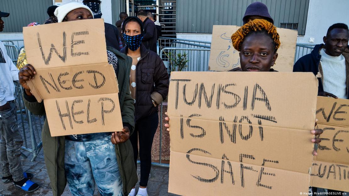 Tunus'taki göçmenler, UNHCR önünde düzenledikleri protesto gösterisinde ellerinde "Yardıma ihtiyacımız var", "Tunus güvenli değil" yazılı pankartlar tutuyor