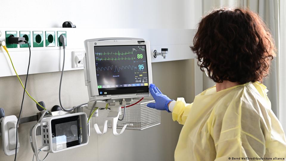 Una enfermera controla un monitor en una habitación de hospital.