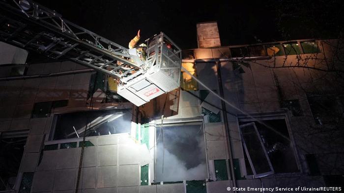 Kiewer Feuerwehrleute im nächtlichen Einsatz an dem durch Drohnenwrackteile beschädigten Gebäude 