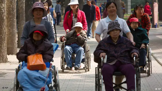 Elderly women in wheelchairs are pushed by care workers while touring a park in Beijing, China, Thursday, April 28, 2011. China's population is aging rapidly and half the people now live in cities, the government said Thursday. (AP Photo/Alexander F. Yuan)
