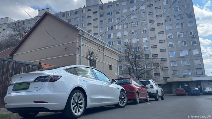 Ein weißer Tesla parkt vor einem alten Wohnblock in Debrecen, Ungarn.