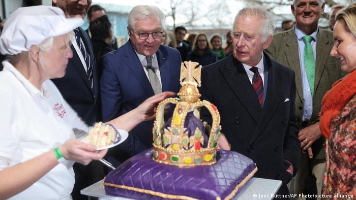 El presidente de Alemania Frank-Walter Steinmeier (izq.) y el rey Carlos (der.) miran una torta con forma de corona en la visita del rey en Alemania. 