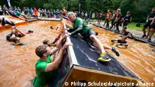 dpatop - Participants of the 'Tough Mudder' manage an water obstacle near Hermannsburg, Germany, 15 July 2017. Crawling, brachiating, jumping, burning off all energy and getting dirty - that is what the obstacle course is about. Photo: Philipp Schulze/dpa +++ dpa-Bildfunk +++