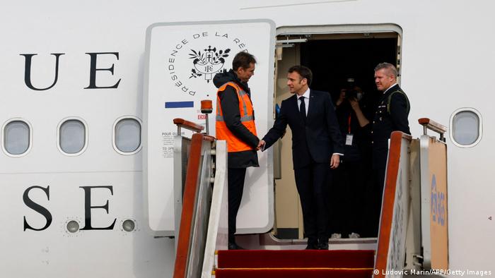 El presidente francés estrecha la mano de un operario tras atravesar la puerta del avión.