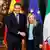 Pedro Sánchez y Giorgina Meloni, se dan la mano frente a las banderas de España, la Unión Europea e Italia.