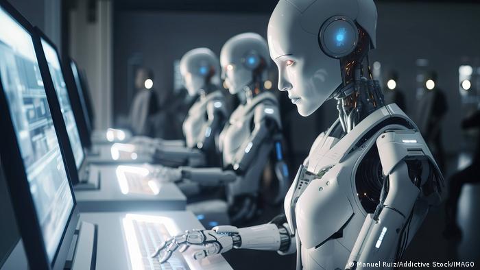 Robots sentados ante unos ordenadores.