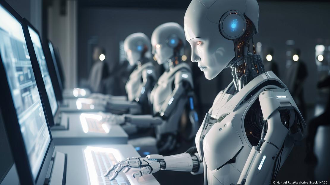 Bilgisayarların başında yan yana oturan insansı robotlar ekranlara bakarak klavyeleri kullanıyor. Yapay zeka sistemlerini simgeleyen görsel, üretken yapay zekayla hazırlanmış.