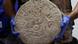 Worker shows circular Mayan scoreboard
