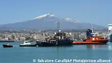 12/04/2023**Backdropped by the Etna Volcano, a ship carrying some 700 migrants onboard enters the Sicilian port of Catania, Wednesday, April 12, 2023. Italy's right-wing government has declared a state of emergency to help it cope with a surge in migrants arriving on the country's southern shores. Premier Giorgia Meloni and her Cabinet on Tuesday, decided to impose the emergency status for six months. (AP Photo/Salvatore Cavalli)