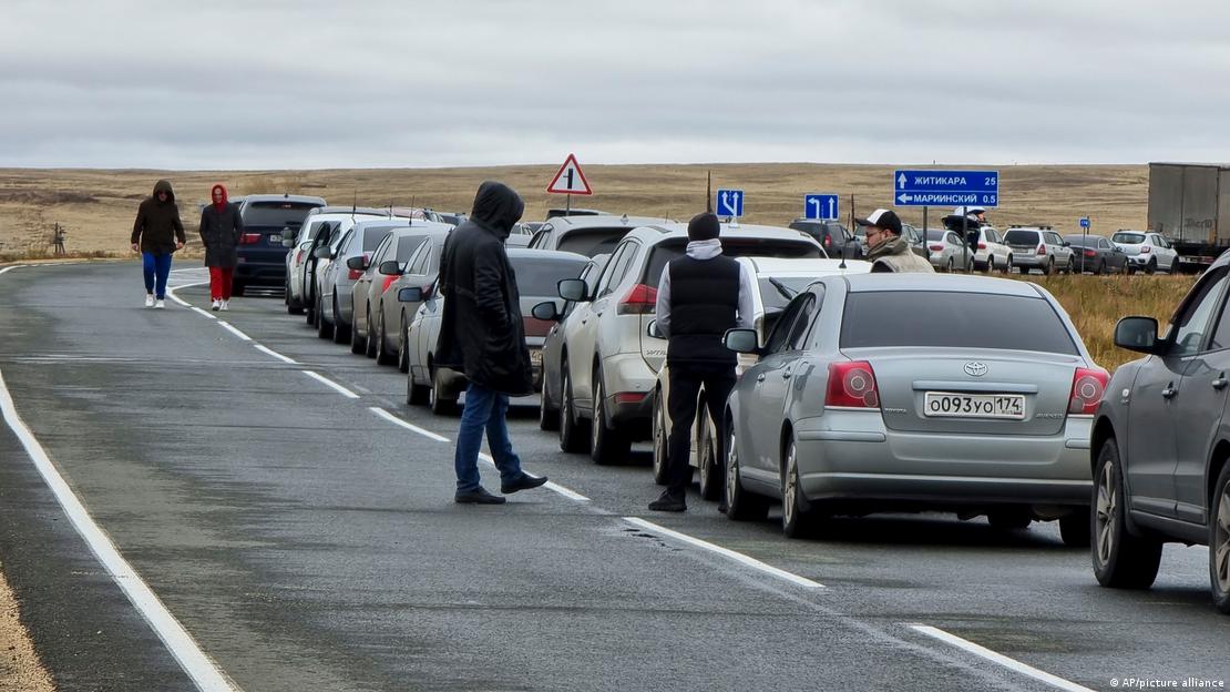 Долга колона возила на пат. Покрај некои од автомобилите стојат или одат мажи.