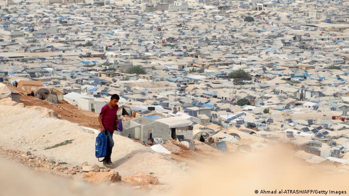 Un joven camina de vuelta a casa en un campamento de refugiados cerca de la frontera con Turquía.