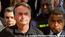 Brazil's Former President Jair Bolsonaro, center, stands outside the Liberal Party's headquarters in Brasilia, Brazil, Thursday, March 30, 2023. Former President Jair Bolsonaro arrived back in Brazil on Thursday after a three-month stay in Florida. (AP Photo/Gustavo Moreno)