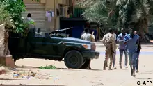 15/04/2023 People run past a military vehicle in Khartoum on April 15, 2023, amid reported clashes in the city. - Sudan's paramilitaries said they were in control of several key sites following fighting with the regular army on April 15, including the presidential palace in central Khartoum. (Photo by AFP)