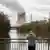 Homem em ponte sobre um rio faz foto de uma usina nuclear soltando vapor