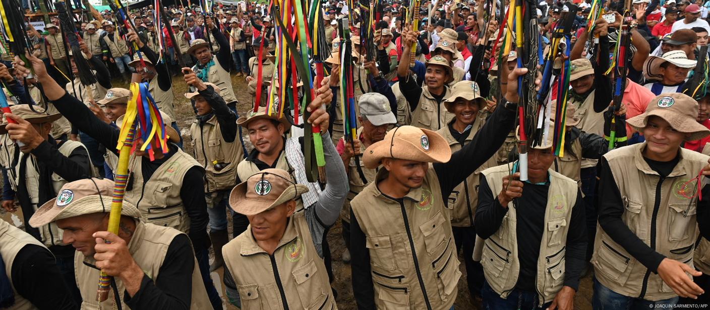 FARC dissidents hold batons in the air at a meeting with local communities