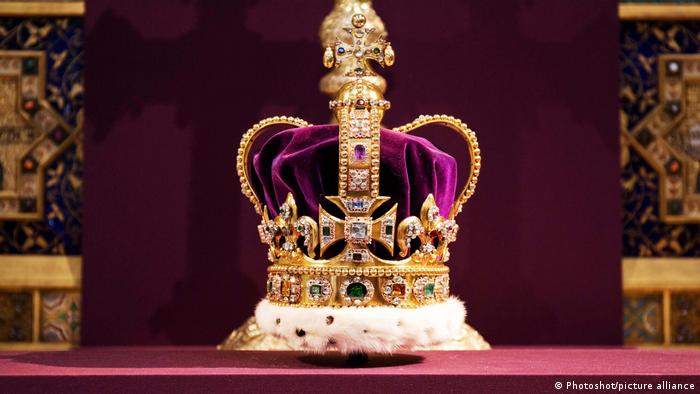 Eine prächtige Krone steht vor einem goldenen und samtenen Hintergrund.
