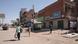 A few people walking past a mostly empty street with shuttered shops in Khartoum A few people walking past a mostly empty street with shuttered shops in Khartoum