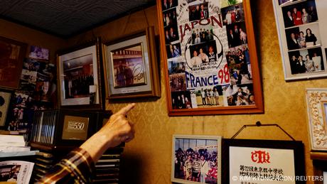 One arm points to old photos on the wall