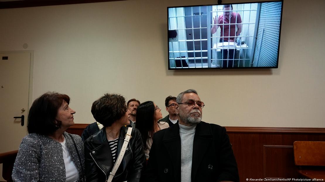 Mother Tatyana, left, and father Valery, right, of Russian opposition activist Ilya Yashin look at a TV screen, as Yashin appears in a video link provided by the Russian Federal Penitentiary Service in a courtroom of the Moscow City Court