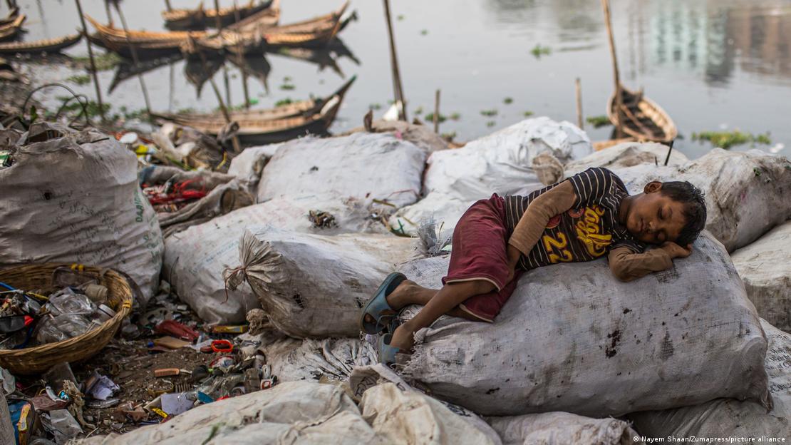 নদীর পাড়ে একটি বস্তার উপর শুয়ে আছে এক শিশু৷