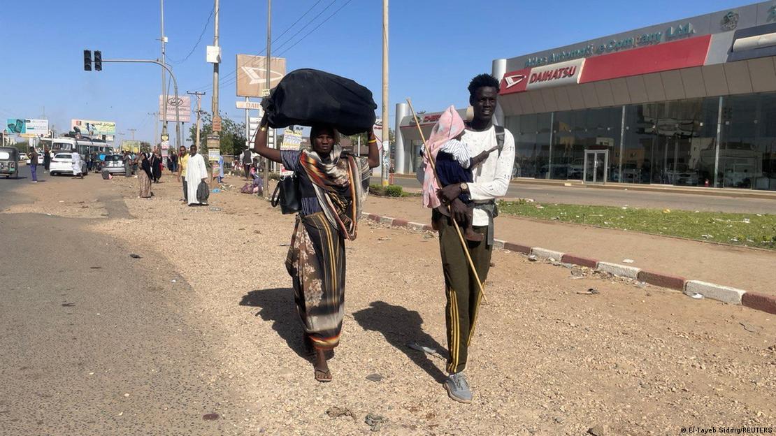 A man and a woman carrying luggage and a baby 