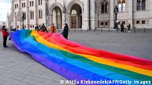 LMBTQ activists deploy a 30-meter-long rainbow-colored flag in front of the Hungarian Parliament building on January 21, 2022 prior to a press conference by Budapest Pride and European Pride Organizers Association (EPOA). - Organizers announced that this year's Budapest Pride Parade will be held in the capital on July 23. Last year, Prime Minister Orban's government passed a law to ban the promotion of homosexuality to minors. The event's organizer Mate Hegedus said that the new regulation has made life difficult for all areas of the LGBTQ community and asks people eligible to vote to cast an invalid ballot for the LGBTQ referendum, which will be held at the same time as the parliamentary elections on April 3. (Photo by ATTILA KISBENEDEK / AFP) (Photo by ATTILA KISBENEDEK/AFP via Getty Images)