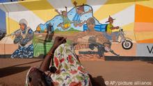 FILE - A woman looks at a mural in Ouagadougou, Burkina Faso, on March 1, 2023. Burkina Faso's government has opened investigations into allegations of human rights abuses by its security forces after a video surfaced that appeared to show the extrajudicial killing of seven children in the countryâ€™s north. A government spokesman said Thursday April 20, 2023 that â€œthe conclusions of the said investigations will lead, if the facts are established, to legal proceedings against the persons responsible.â€ (AP Photo, File)