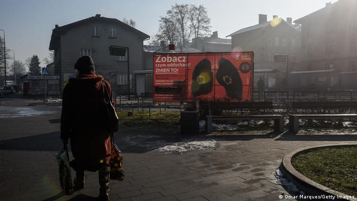 A person walks past a poster drawing attention to air pollution from polluting coal heating in Poland