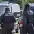 Arkası dönük iki polis memur, minibüslerin önünde duruyor