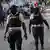 Agentes de policía caminan cerca de personas que cargan con sus pertenencias mientras huyen de sus hogares y vecindarios debido a enfrentamientos entre bandas, en Puerto Príncipe. (Archivo 24.04.2023)
