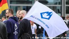 Ein Mitglied der Jungen Alternative, der Jugendorganisation der AfD, trägt auf einer Wahlkampfveranstaltung eine Fahne mit dem Logo der Organisation.