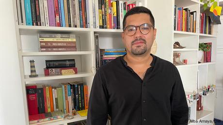 Oscar Martinez photographed, with a book case in the background