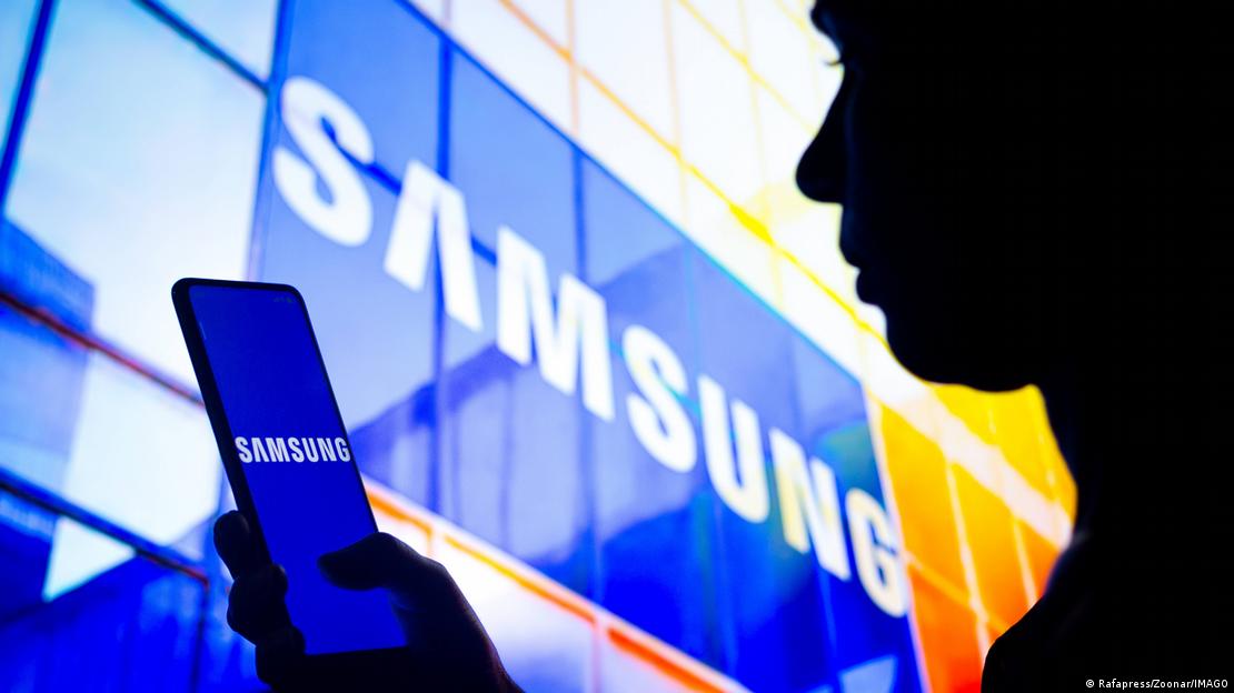 Bir kişi, Samsung logosunun önünde Samsung marka telefon tutuyor