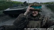 26/04/2023**A Ukrainian soldier holds his helmet as he rides an APC in Bakhmut, in the Donetsk region, Ukraine, Wednesday, April 26, 2023. (AP Photo/Libkos)