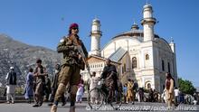 A Taliban fighter stands guard as Afghan people attend Eid al-Fitr prayers, marking the end of the holy fasting month of Ramadan, in Kabul, Afghanistan, Friday, April 21, 2023. (AP Photo/Ebrahim Noroozi)