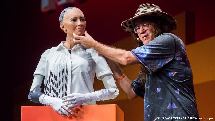 Un hombre junto a un robot humanoide.
