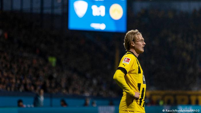 Borussia Dortmunds Spieler Julian Brandt steht enttäuscht auf dem Feld, im Hintergrund ist die Anzeigetafel mit dem Endergebnis zu sehen