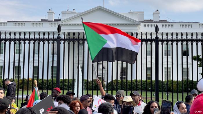 USA Forderung nach Intervention im Sudan in Washington: Menschen stehen vor dem Zaun des Weißen Hauses in Washington, eine Person schwenkt eine sudanesische Fahne