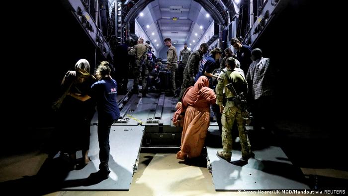 Sudan Konflikt l Evakuierung britischer Staatsangehöriger nach Zypern: Blick in den Frachtraum eines Flugzeuges, in den im Dunkeln Personen einsteigen und andere sich bereits an Bord befinden