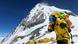 A climber clad in yellow climbing gear and oxygen tanks, against the backdrop of Mount Everest A climber clad in yellow climbing gear and oxygen tanks, against the backdrop of Mount Everest