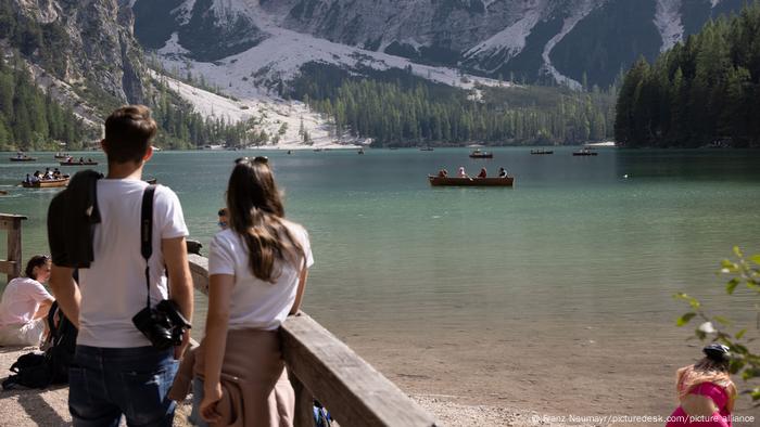 Ein junges Paar schaut auf den Pragser Wildsee, auf dem Boote fahren, Südtirol