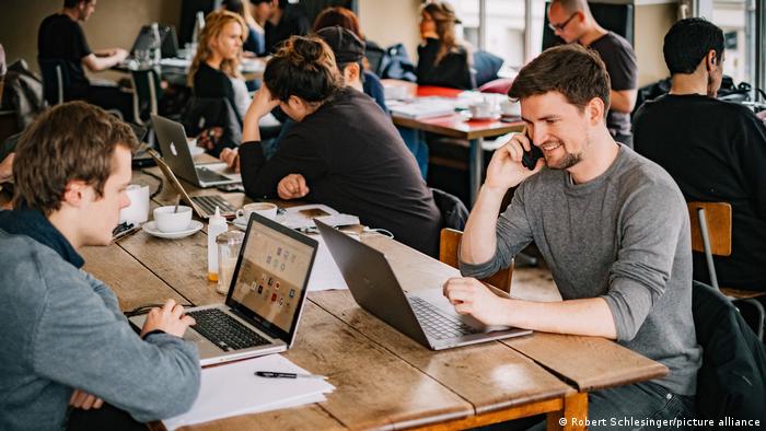Mehrere Menschen sitzen vor ihren Laptops in einem Coworking Space in einem Café in Berlin 