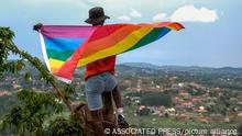 A gay Ugandan man holds a pride flag as he poses for a photograph in Uganda Saturday, March 25, 2023. A prominent leader of Uganda's LGBTQ community on Thursday described anguished calls by others like him who are concerned for their safety after the passing of a harsh new anti-gay bill. (AP Photo)