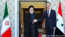 In this photo released by the office of the Iranian Presidency, President Ebrahim Raisi, left, is welcomed by his Syrian counterpart Bashar Bashar in Damascus, Syria, Wednesday, May 3, 2023. (Iranian Presidency Office via AP)
